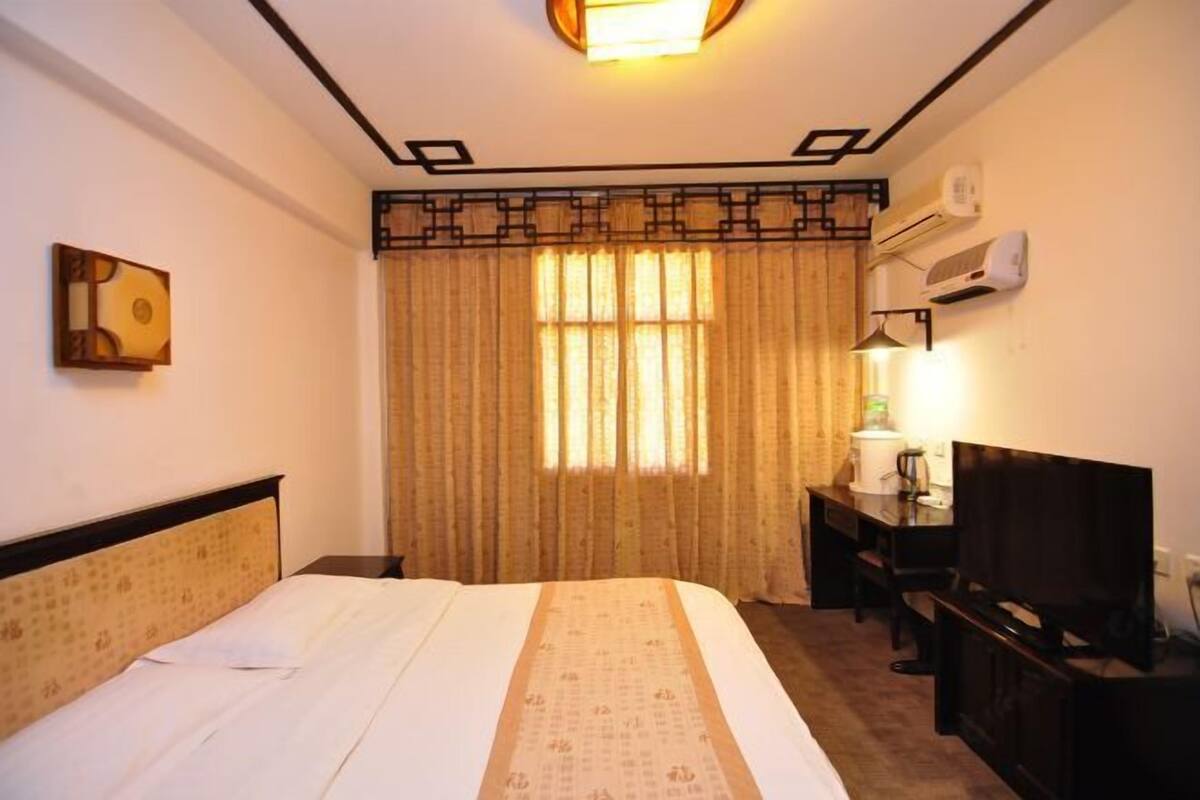 Une chambre d’hôtel équipée d’un lit, d’un bureau avec une chaise, d’une télévision et d’un appareil de climatisation.