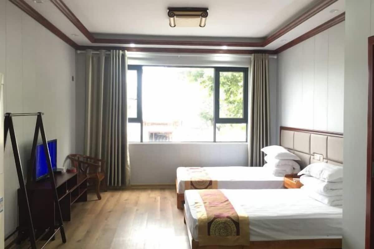 A hotel room with two beds, a desk with a computer, and a window with curtains.