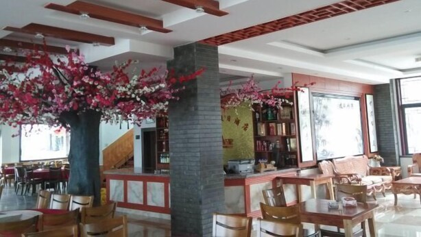 Un vestíbulo de hotel con vigas de madera, mostrador de recepción, zona de estar y ventanas amplias.