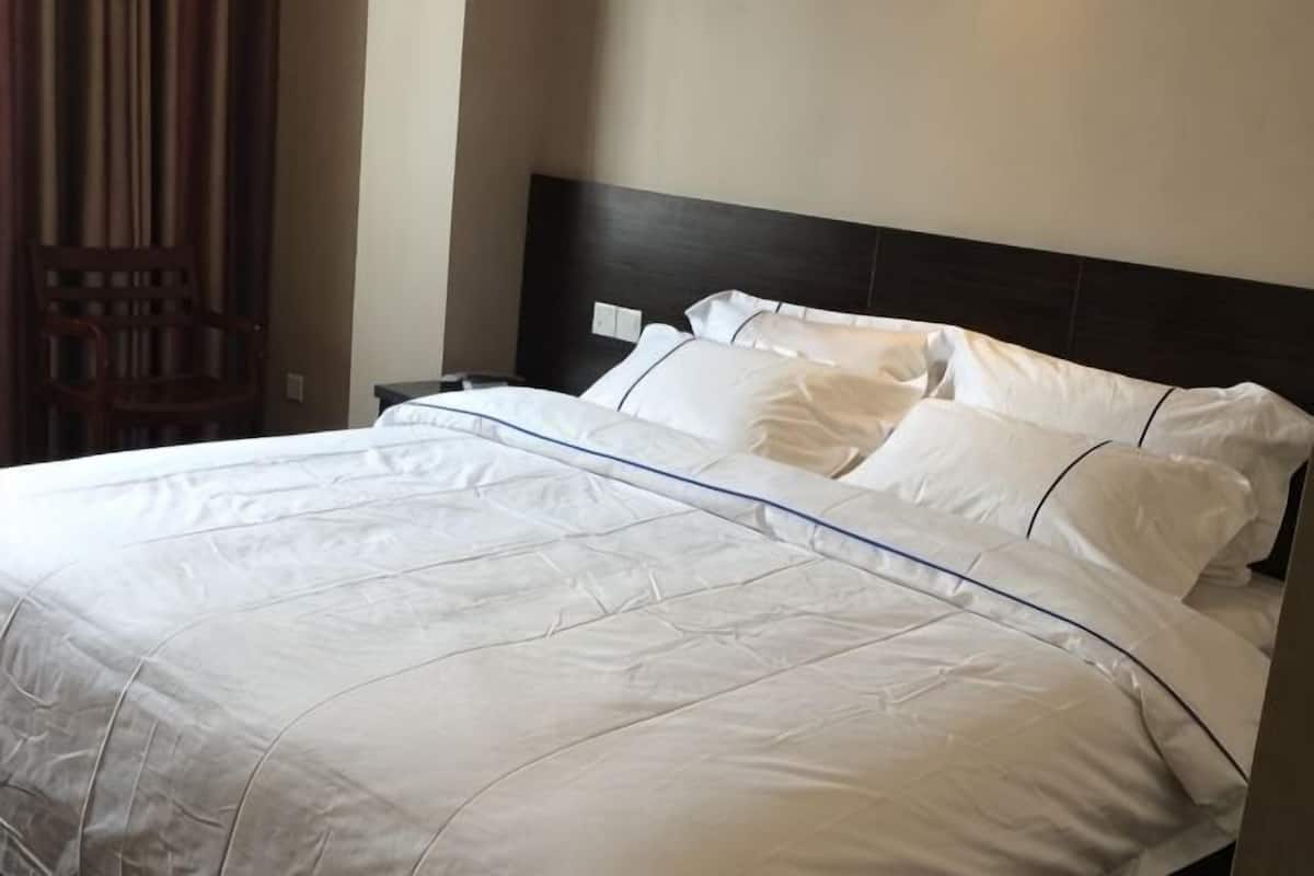 A neatly made bed with white linens and a dark headboard.