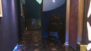 Ein Flur mit dunklem Marmorboden, einer Tür mit gefrostetem Glasschild und einer Wand mit dekorativem Muster.