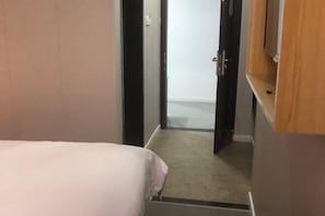A narrow hallway with a bed on the left and a door leading to another room on the right. - Fengxing Hostel (Shanghai)