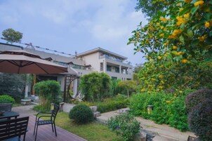 Un patio con mobiliario exterior, una zona de estar cubierta y vistas a un edificio de varios pisos.