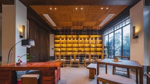 A modern interior with wooden ceiling and walls, a bar area with stools, and a wall of illuminated bottles. - Ever-Joy Muxin Xiangcun Hotel (Yixing)