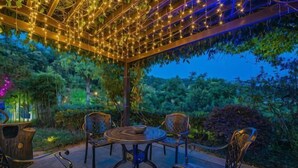 An outdoor seating area with a pergola, string lights, and surrounding greenery. - Ever-Joy Muxin Xiangcun Hotel (Yixing)