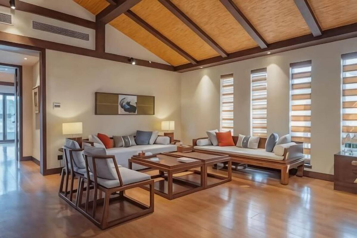 Un salón amplio con techo alto, vigas de madera, un conjunto de sofás y una mesa de centro.
