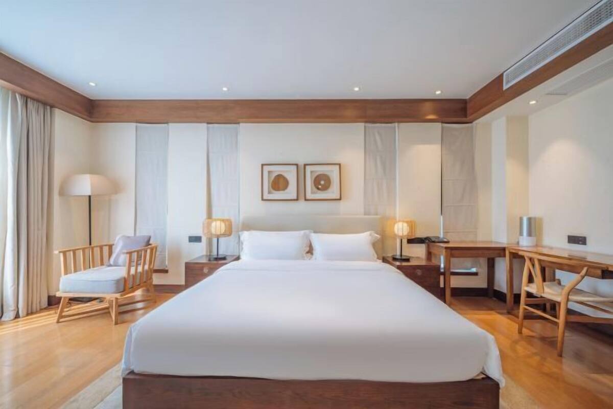 Una habitación de hotel con una cama grande, muebles de madera y dos lámparas fijadas a la pared.