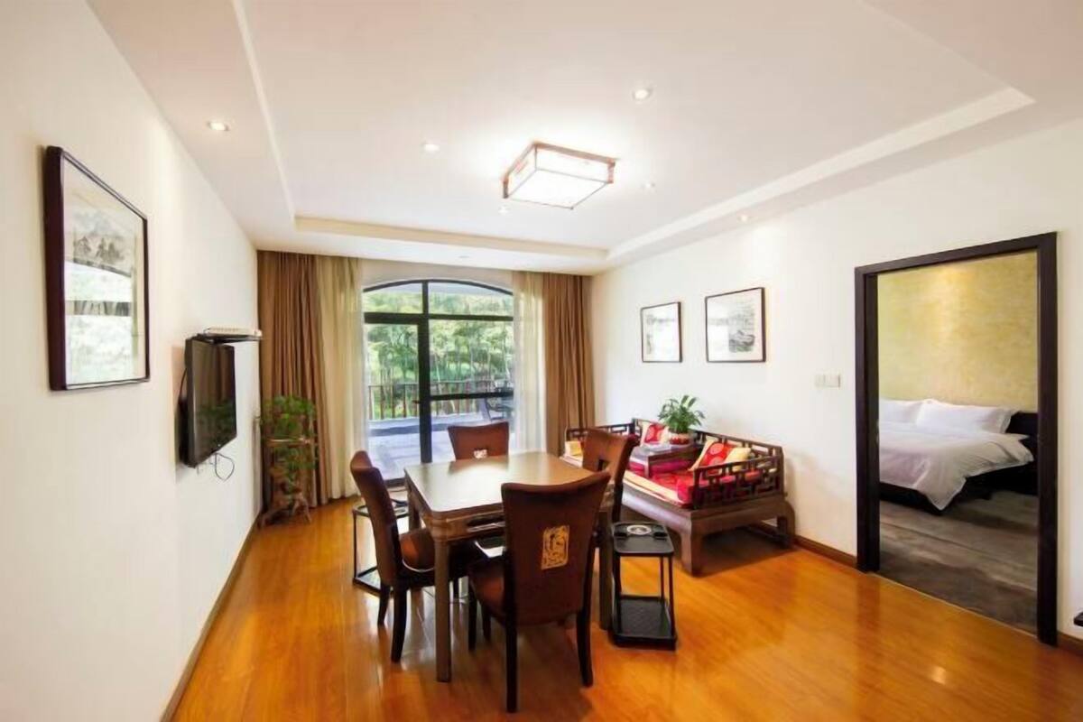 Una habitación de hotel con zona de comedor, cama y televisor.