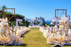 Un salón de bodas al aire libre con un sendero despejado que conduce a un arco decorado.