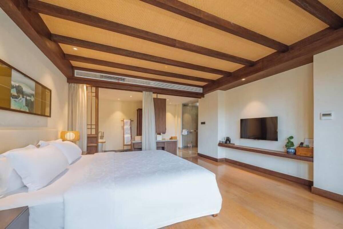 Una habitación de hotel con una cama grande, un televisor y un techo de madera.