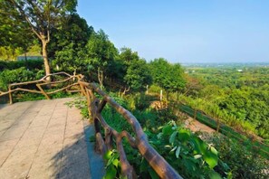 A paved walkway with a rustic wooden railing, surrounded by lush greenery and trees. - Ever-Joy Muxin Xiangcun Hotel (Yixing)