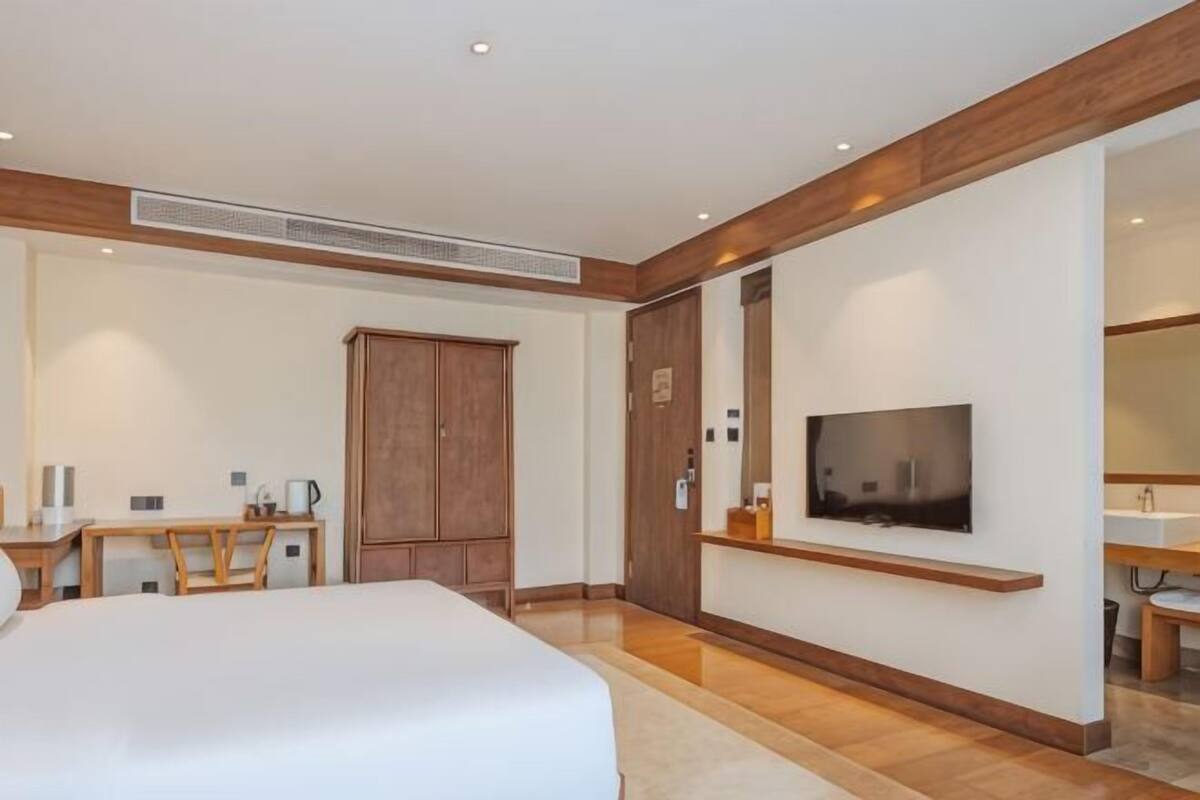 Habitación de hotel con cama, escritorio, televisor y armario.