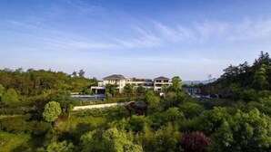 A large, modern building with multiple levels and a prominent swimming pool. - Ever-Joy Muxin Xiangcun Hotel (Yixing)