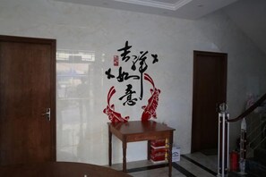 A room with a wooden door, a table with a box, and a wall with calligraphy. - Blue Xinhai Homestay (Shengsi)