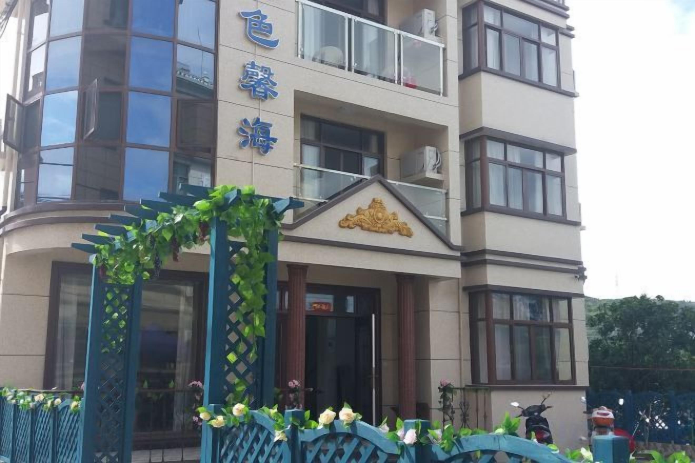 A multi-story hotel with a balcony on the upper floor, a decorative entrance arch, and a sign with Chinese characters.