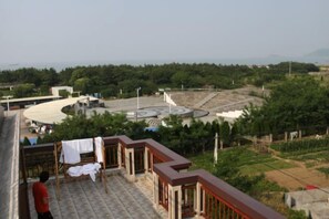 A balcony with a view of a landscaped area, including a circular structure and greenery. - Blue Xinhai Homestay (Shengsi)