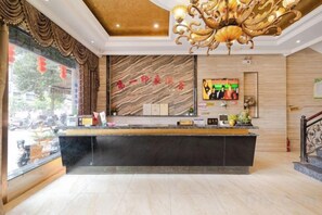 A hotel reception area with a marble wall, a reception desk, and a chandelier. - renshoudiyiyinxiangdajiudian (Renshou)