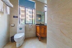 A bathroom with a toilet, sink, and window.