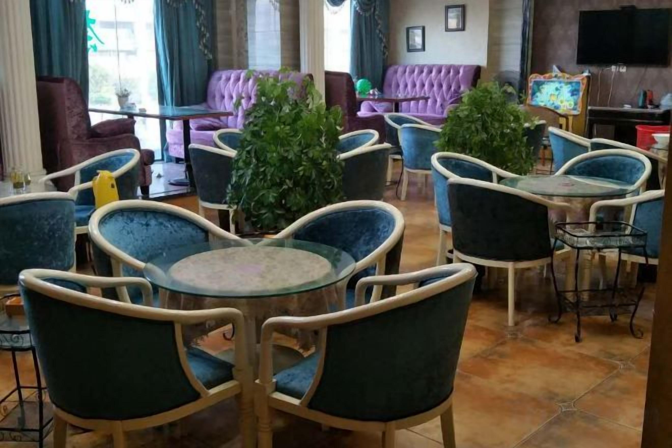 A hotel lobby with round tables and chairs, a sofa area, and a television.