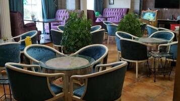 A hotel lobby with round tables and chairs, a sofa area, and a television.