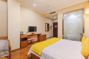A hotel room with a bed, a desk, a chair, a television, and a door. - renshoudiyiyinxiangdajiudian (Renshou)