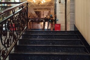 A staircase with a metal railing leading to a landing. - renshoudiyiyinxiangdajiudian (Renshou)