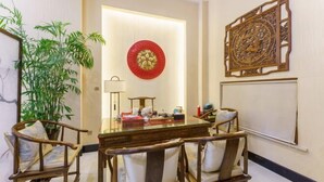 A room with a wooden table, chairs, a potted plant, and decorative wall art.