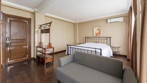Una habitación de hotel con una cama, un sofá, un armario de madera y una pequeña mesa.