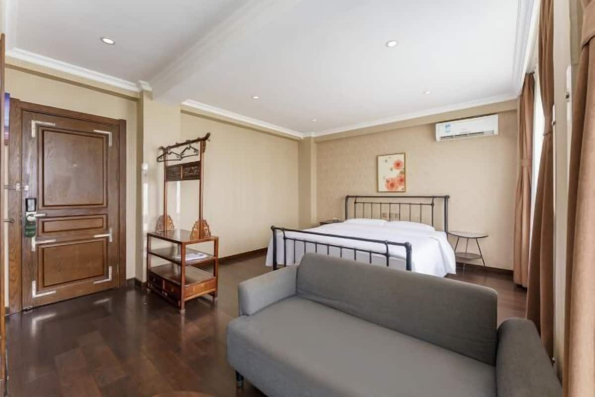 Una habitación de hotel con una cama, un sofá, un armario de madera y una pequeña mesa.