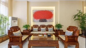 Un salón comedor de estilo tradicional con un conjunto de sofás, una mesa de centro y plantas decorativas.