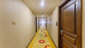 Un pasillo de hotel con piso alfombrado, puertas de madera y una lámpara en el techo.