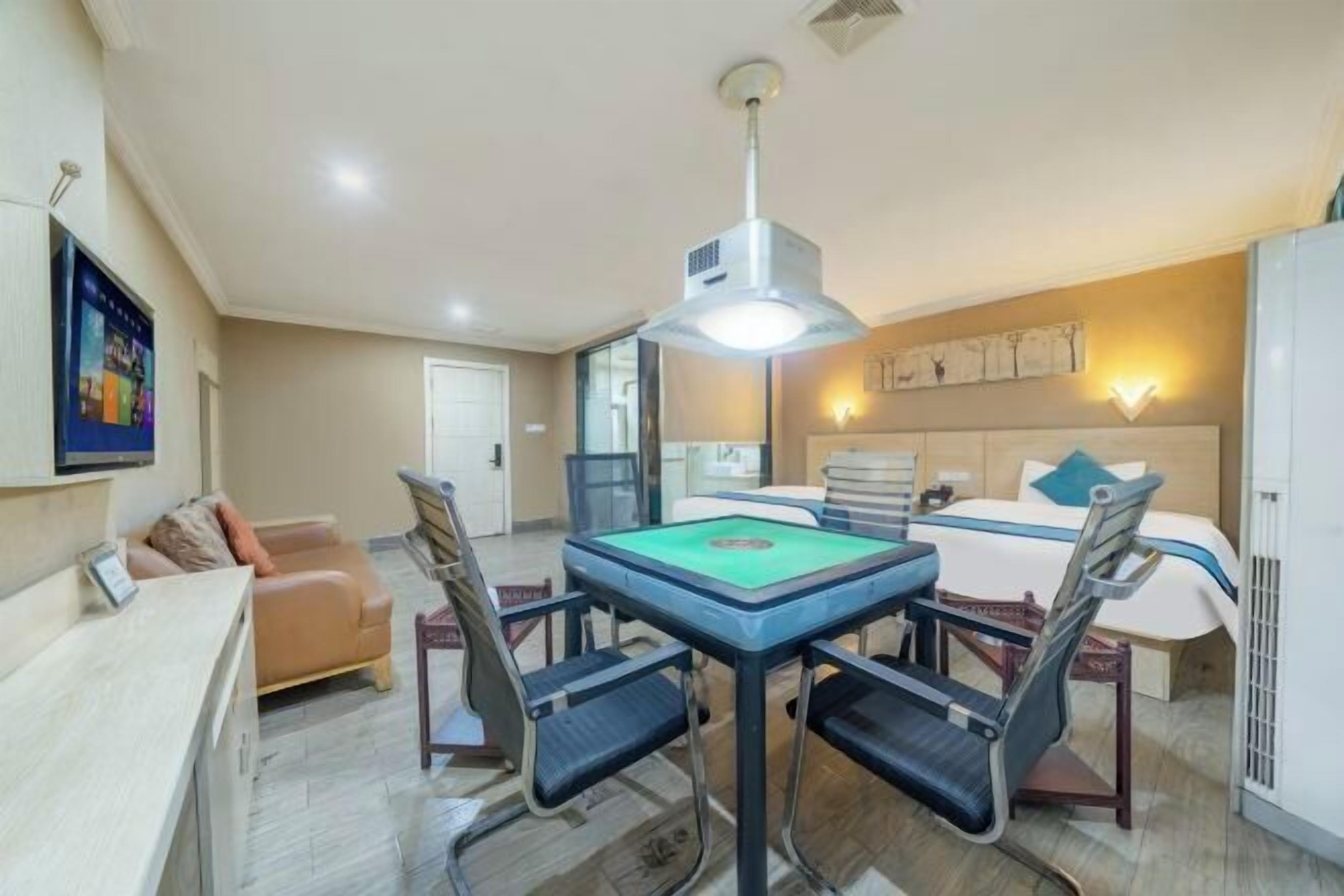 Een hotelkamer met een pooltafel, een bed met hoofdbord, een bank en een bureau.
