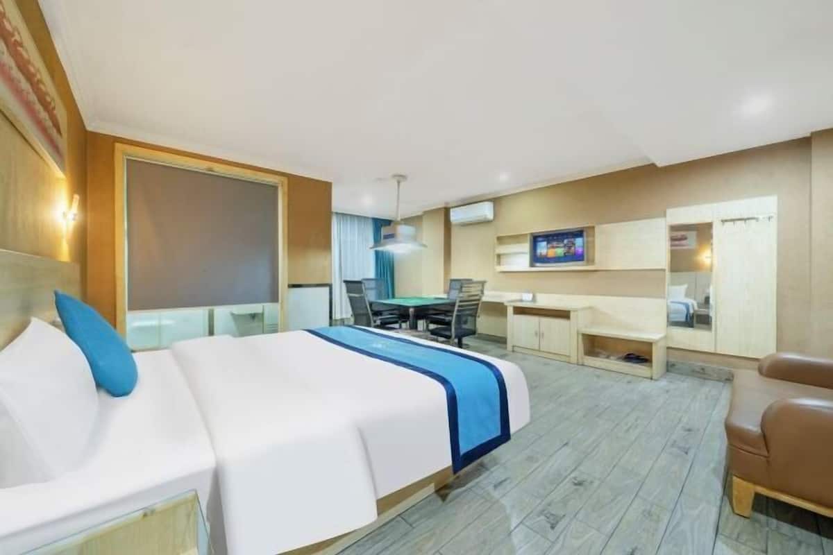 Ein Hotelzimmer mit Bett, Schreibtisch, Stuhl und Fernseher.