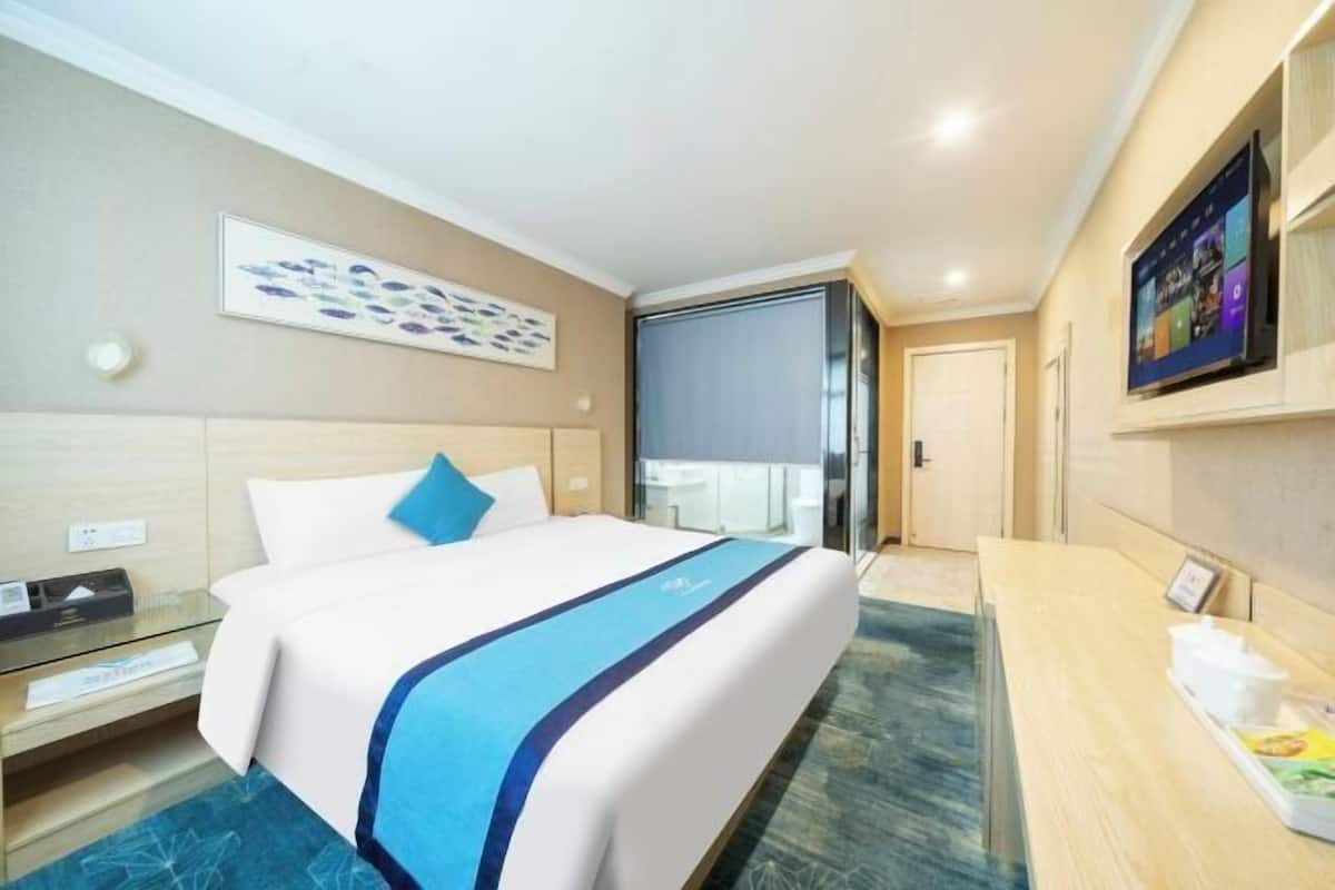 Ein Hotelzimmer mit Bett, Schreibtisch, Fernseher und einem Gemälde an der Wand.