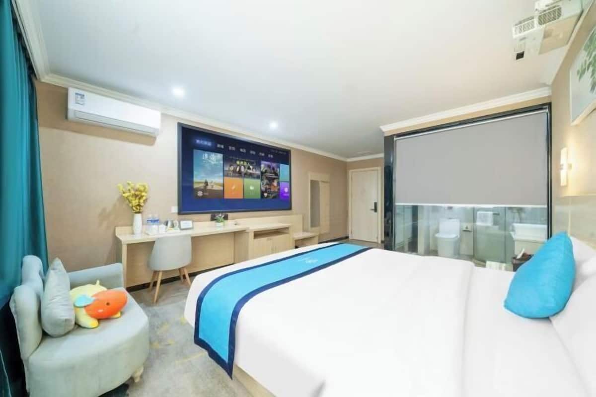 Ein Hotelzimmer mit Bett, Schreibtisch, Fernseher und Fenster.