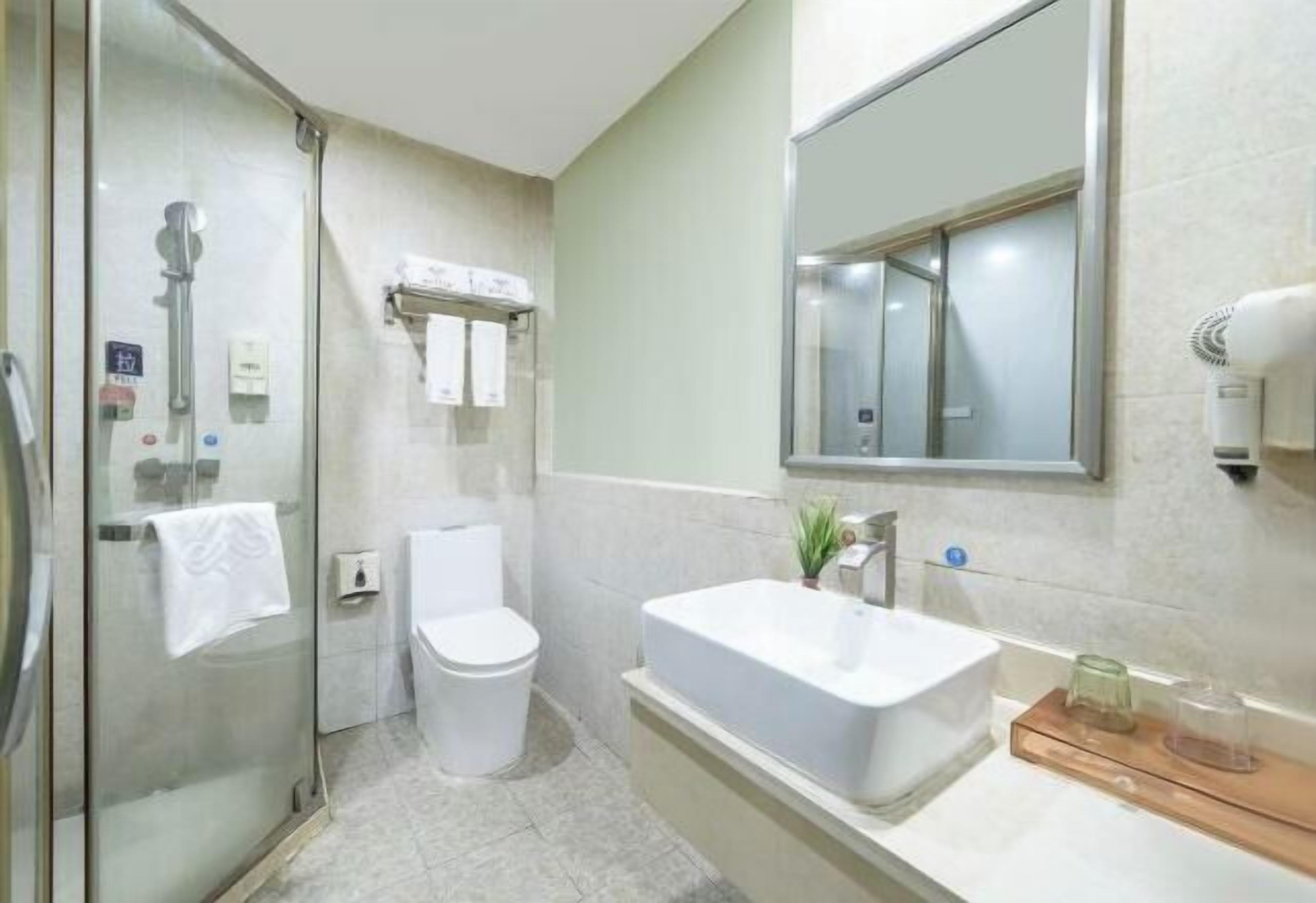 Een moderne badkamer met een douchecabine van glas, een wit toilet, een vrijstaand bad en een grote spiegel boven de wastafel.