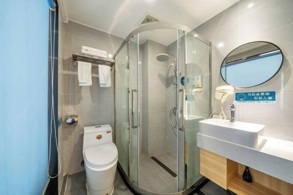 A modern bathroom with a glass-enclosed shower, a white sink, and a toilet.