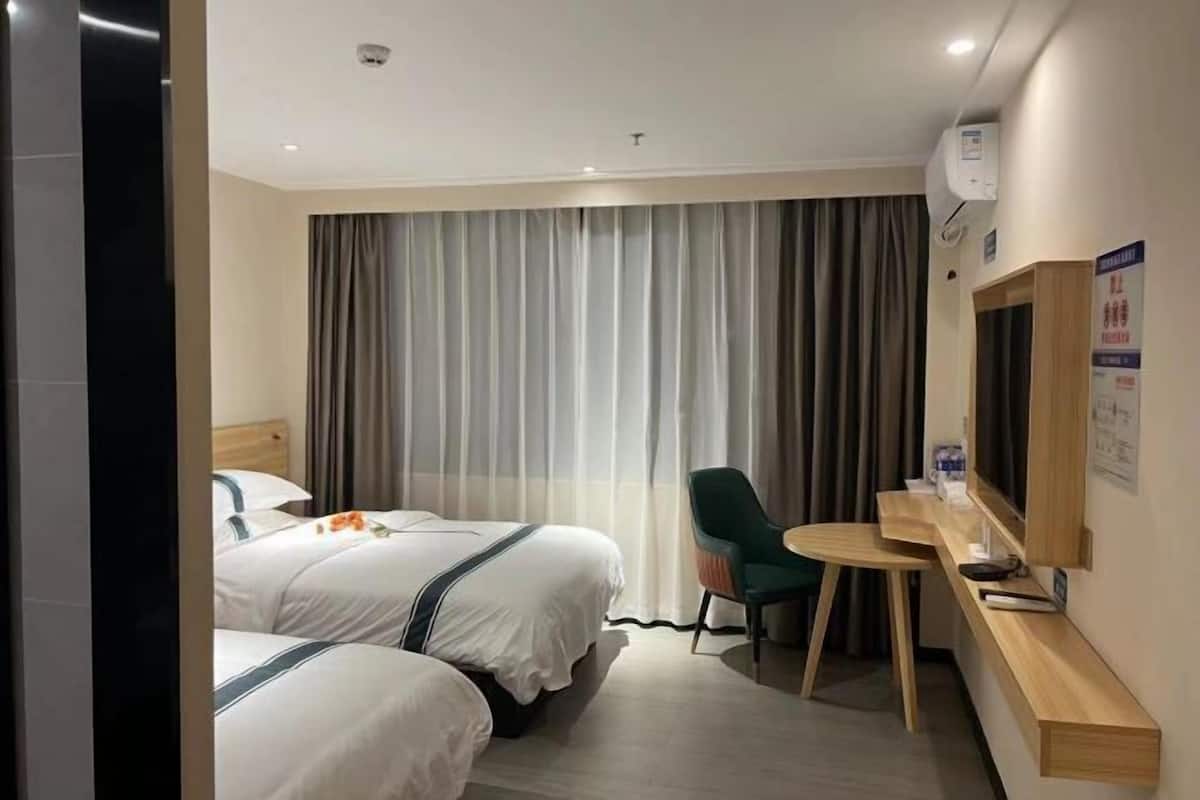 Une chambre d’hôtel avec deux lits, un bureau, une chaise et un téléviseur.