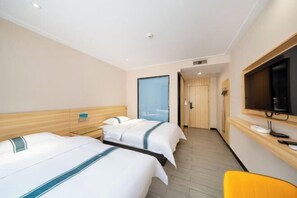 A hotel room with two beds, a television, and a desk.