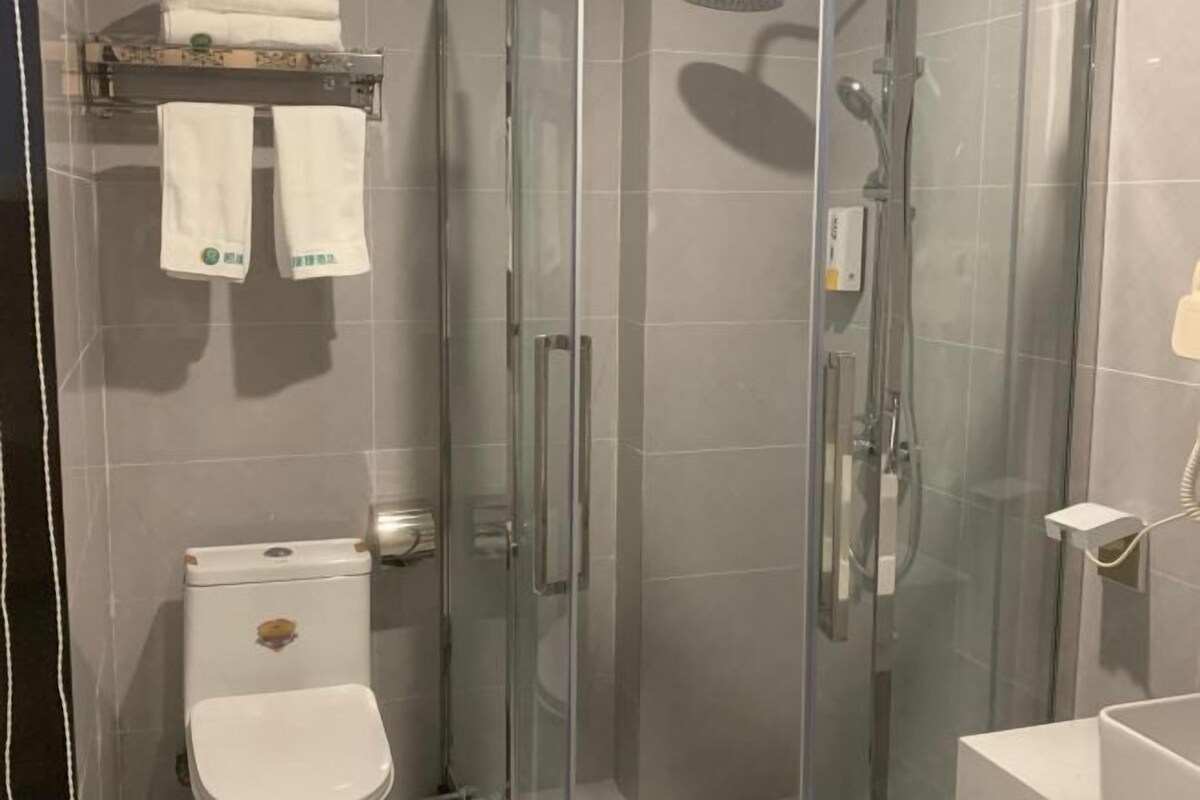A modern bathroom with a glass-enclosed shower, a toilet, and a sink.