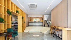 A modern hotel lobby with wooden shelving, a reception desk, a staircase, and seating areas. - Kaimei Convenience Hotel (Nanning Jinxiang Avenue Subway Station) (Nanning)