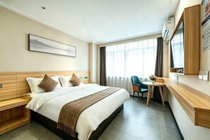 Ein Hotelzimmer mit Bett, Nachttisch, Schreibtisch, Stuhl und einem Fenster mit Vorhängen.