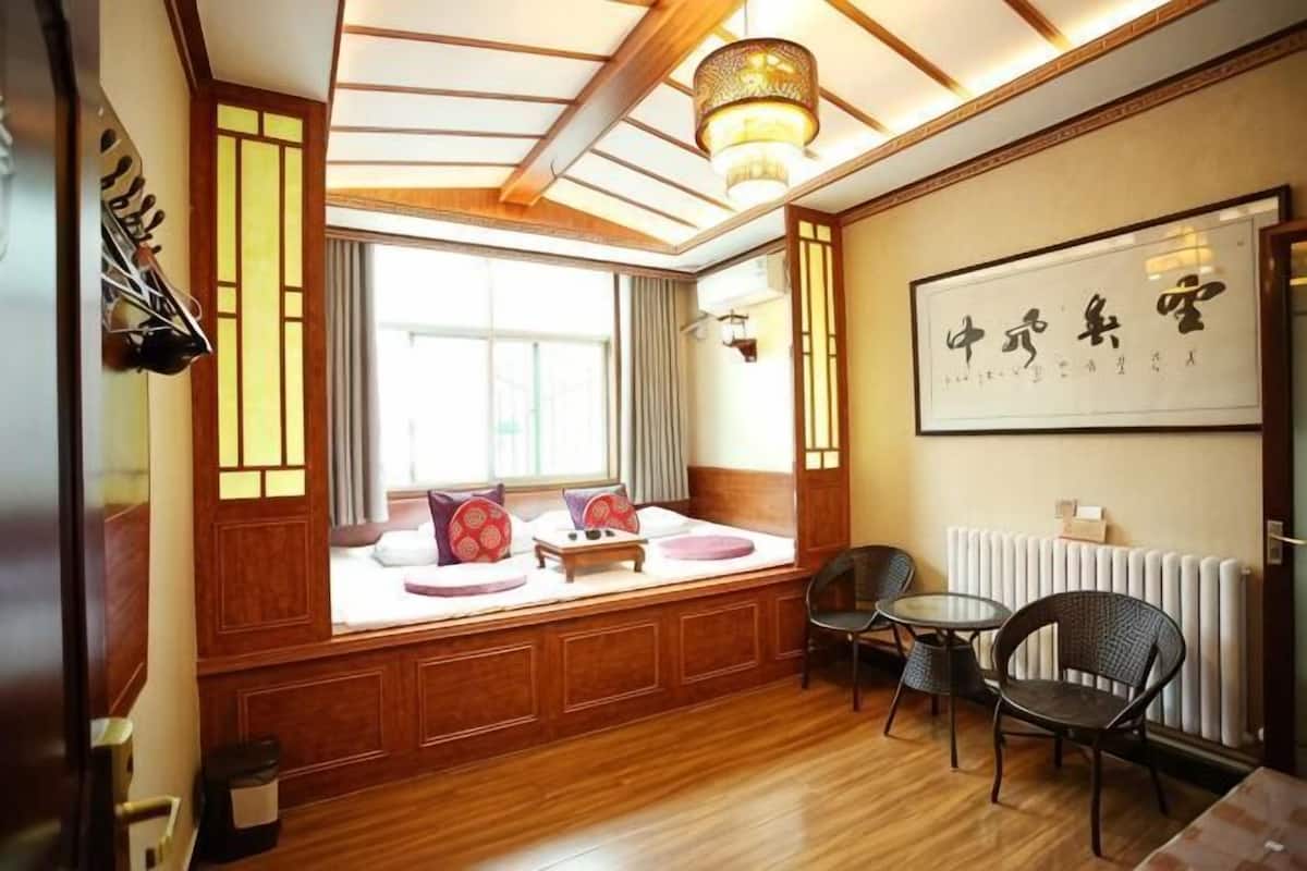 A traditional Japanese-style room with tatami flooring, a low wooden table, and a large window with a view.