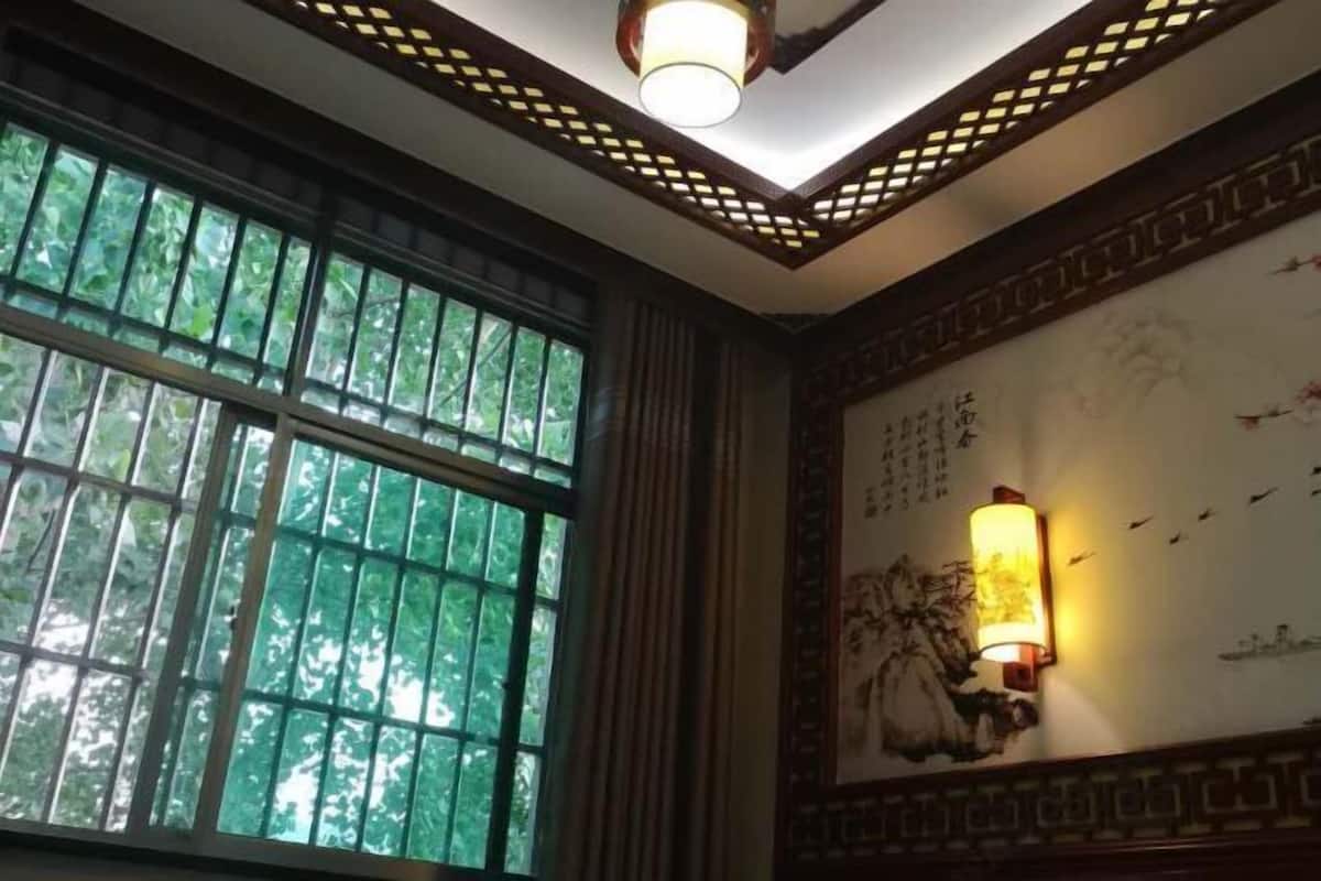 A room with a large window, a wall-mounted light fixture, and a decorative wall panel.