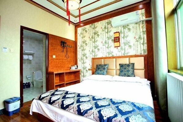 A bedroom with a bed, a wooden headboard, a nightstand, a mirror, and a window with curtains. - Qinyong Scenic Area Inn (Xi'an)