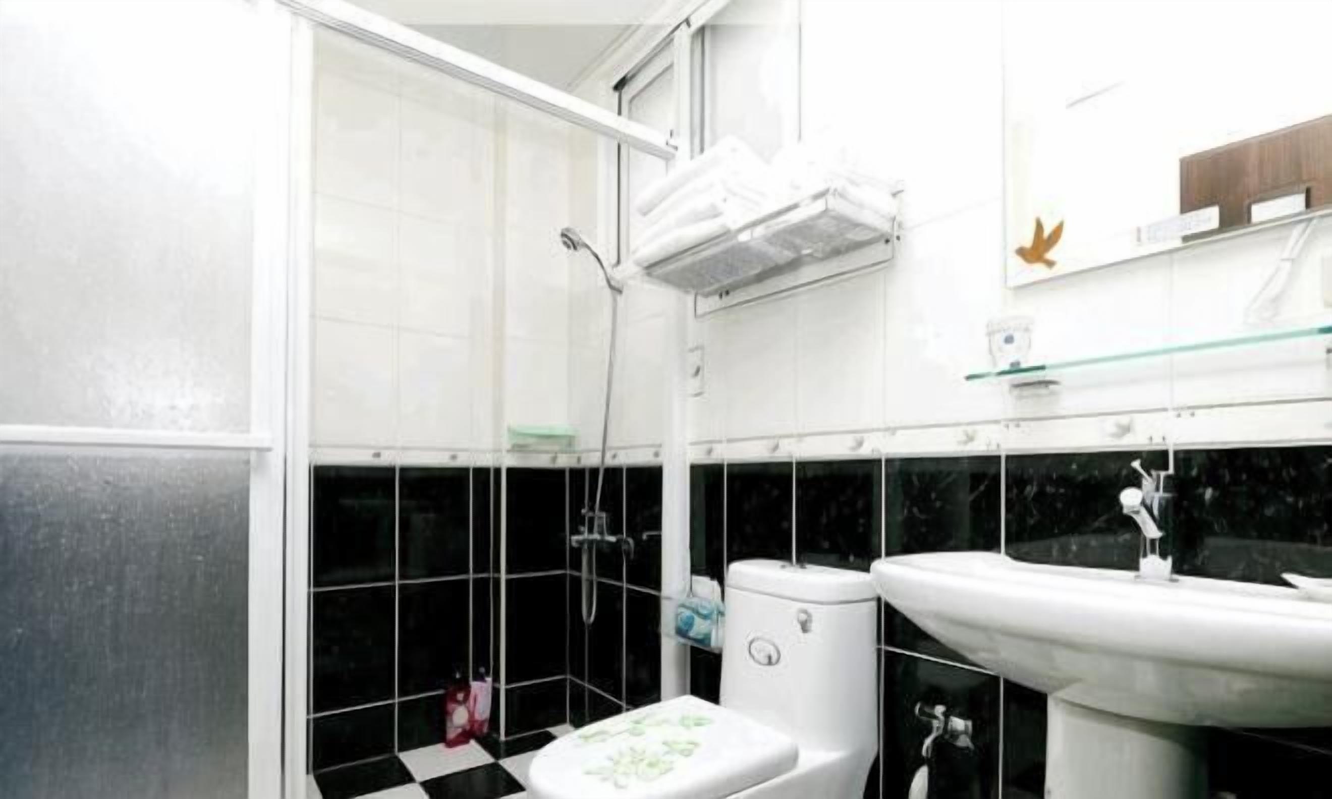 Un baño con ducha, inodoro, lavabo y estante de vidrio.