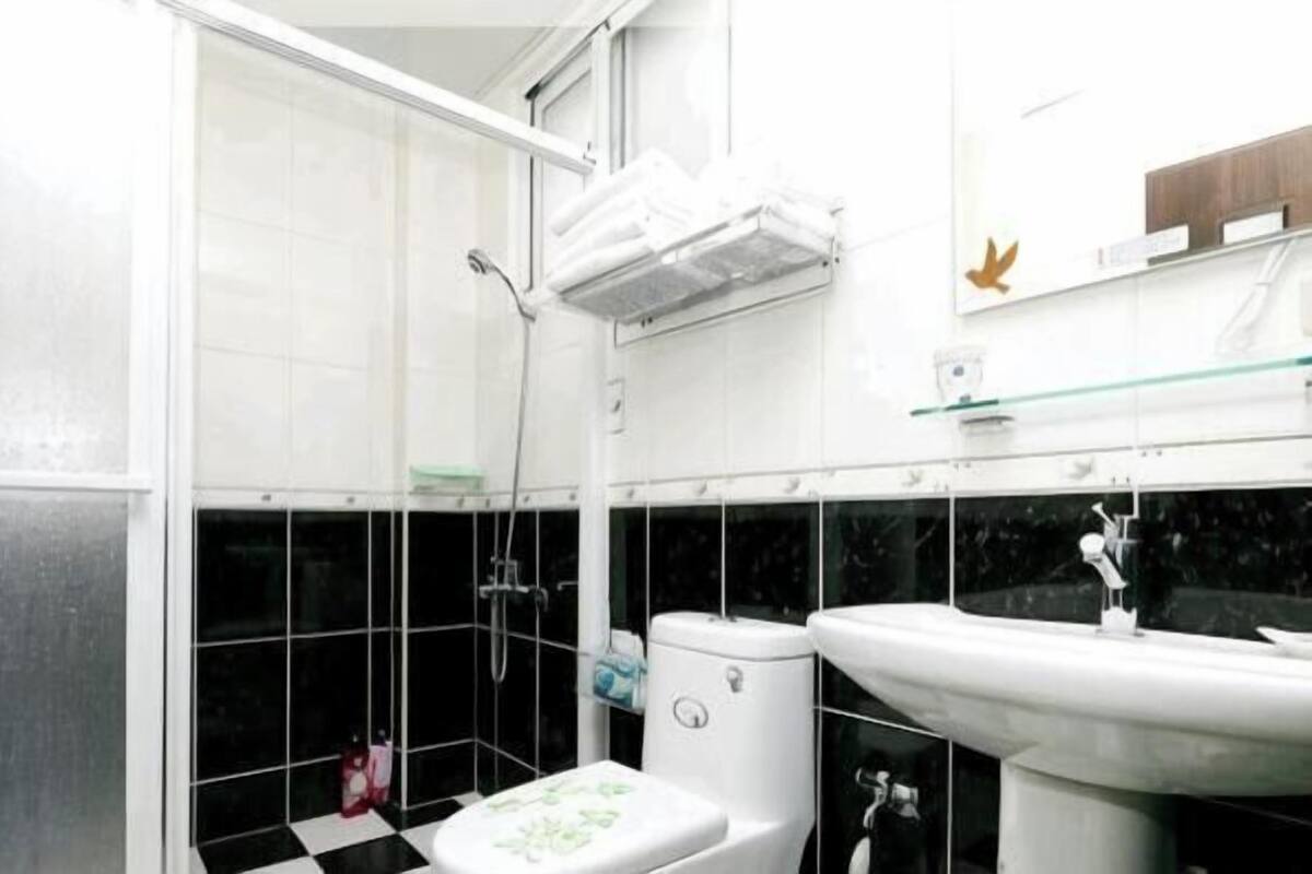 Un baño con ducha, inodoro, lavabo y estante de vidrio.