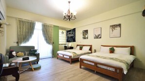 A room with two wooden beds, a green sofa, a round coffee table, and a chandelier. - Rover 21 Inn (Taitung)
