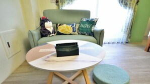 A room with a round table, a green sofa with patterned cushions, and a green ottoman. - Rover 21 Inn (Taitung)