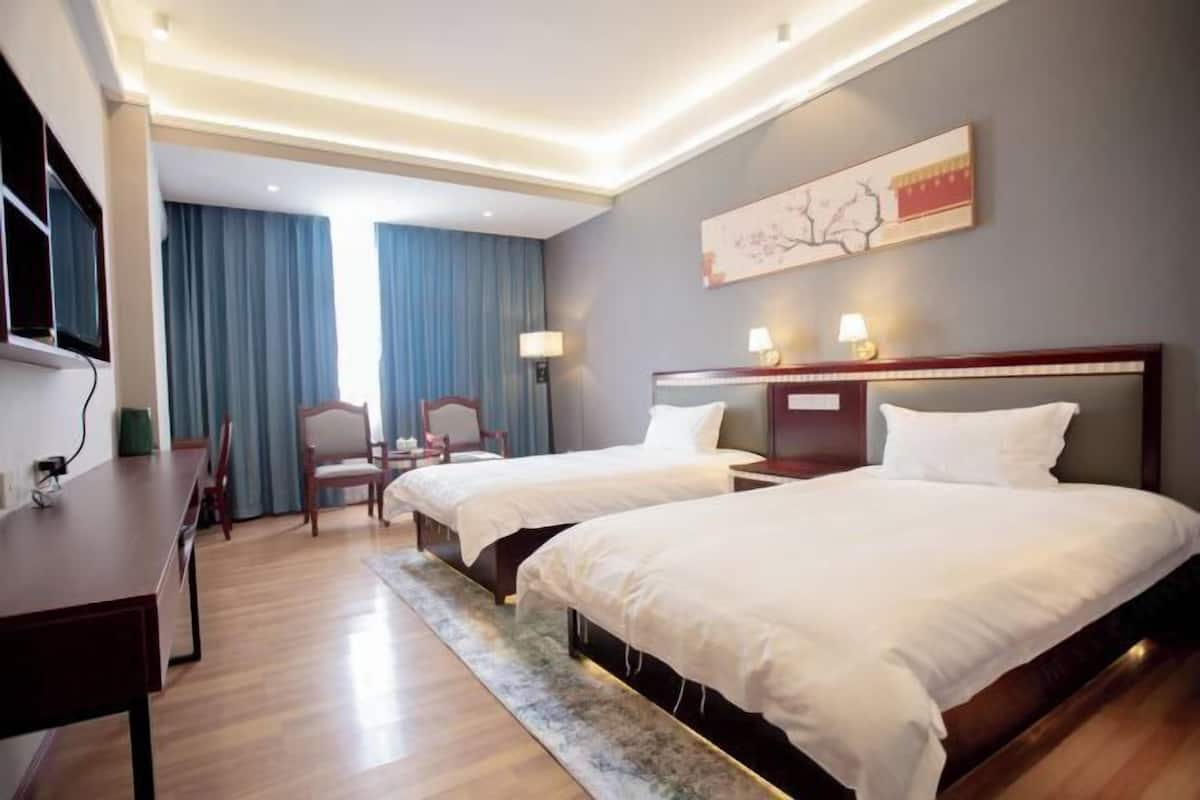 Habitación de hotel con dos camas, un escritorio y un televisor.